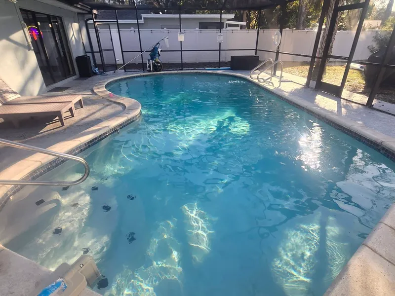 A crystal clear screened-in pool after a weekly cleaning visit